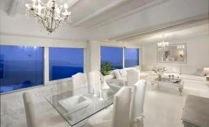 Biały salon ze szklanym stołem i krzesłami w obiekcie Paradisiacal Villa with Pool and Sea View in Mykonos w mieście Agios Ioannis