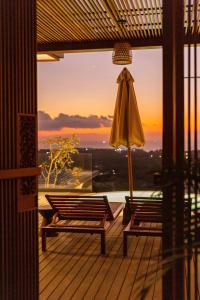an umbrella and two chairs on a deck with the sunset at Grün Resort Uluwatu in Uluwatu
