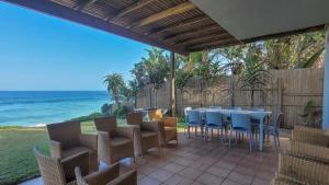 a patio with a table and chairs and the ocean at Salties Beach House KwaZulu-Natal in Sheffield Beach
