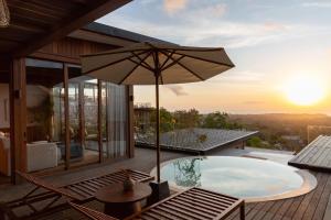 a patio with a hot tub and an umbrella at Grün Resort Uluwatu in Uluwatu