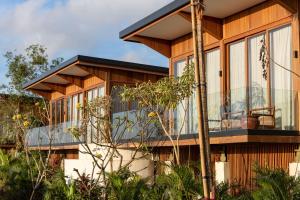 a house with a wrap around porch with a balcony at Grün Resort Uluwatu in Uluwatu