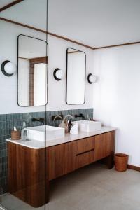 a bathroom with two sinks and two mirrors at Grün Resort Uluwatu in Uluwatu