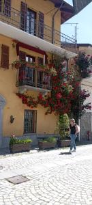 a woman standing in front of a building with flowers at Casa Marmo in Fenestrelle