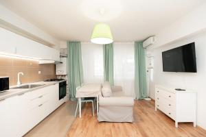 Il comprend une cuisine avec des placards blancs, une table et une télévision. dans l'établissement The Shiny Apple, à Dobroeşti 21 autres photos