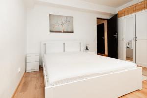 une chambre blanche avec un grand lit blanc dans l'établissement The Shiny Apple, à Dobroeşti