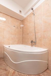 une baignoire blanche dans une salle de bain aux murs carrelés dans l'établissement The Shiny Apple, à Dobroeşti
