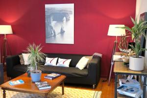 - un salon avec un canapé et un mur rouge dans l'établissement Hotel d'Angleterre Etretat, à Étretat