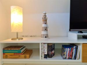 a book shelf with a lighthouse and a lamp and books at Fewo Grachtenhimmel- Appartement zum Entspannen in Krummhörn