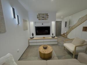 ein Wohnzimmer mit Fernseher, Couch und Tisch in der Unterkunft Villa Harmonie - Luxe, Jaccuzzi et Piscine en Charente-maritime in Saint-Ciers-du-Taillon