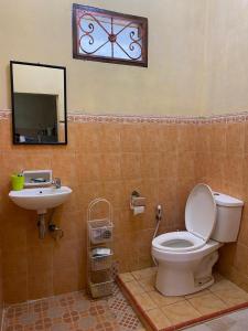 a bathroom with a toilet and a sink and a clock at 'Nanini Backyard' Home Stay in Berastagi +19 photos