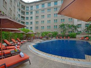 a hotel with a swimming pool with chairs and umbrellas at PARKROYAL Yangon in Yangon