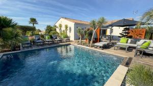 ein Swimmingpool mit Liegestühlen und ein Haus in der Unterkunft Villa Harmonie - Luxe, Jaccuzzi et Piscine en Charente-maritime in Saint-Ciers-du-Taillon