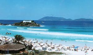 a group of people on a beach with the ocean at Apt a 500m da praia do forte in Cabo Frio