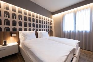 a bedroom with a large white bed and a window at Stemor Visionary Apartments in Desenzano del Garda +21 photos