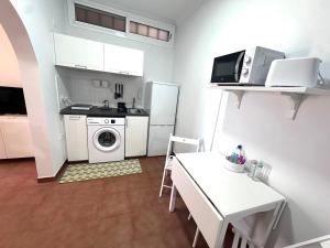 a small white kitchen with a table and a microwave at El Rincón de Pancho in Guía de Isora