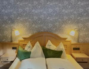 een slaapkamer met een bed met groene en witte kussens bij Heutaler Hof - Hotel im Naturidyll in Unken