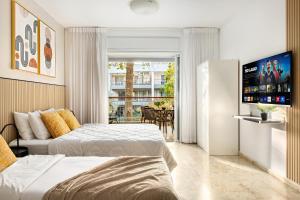 a hotel room with two beds and a flat screen tv at Royal Park Apartments Resort by Sea N Rent in Eilat +286 photos