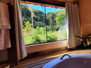 bagno con finestra affacciata sulle montagne di Vale do Piemonte - Chalé com hidromassagem - a Santo Antônio do Pinhal