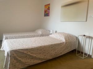 a bedroom with two beds and a table with a bedspread at Breve Sosta in Santhià