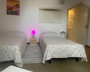 two beds in a bedroom with a pink lamp at Breve Sosta in Santhià