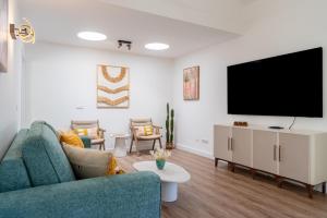 a living room with a blue couch and a flat screen tv at Villa Las Marias Suite - Playa Roca Residence in Costa Teguise