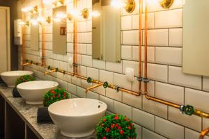 a bathroom with four sinks and flowers on a counter at UrbanKey Pods - Vienna Neubau in Vienna