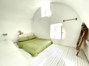 a bedroom with a green bed in a white room at 19th Century Vaulted Villa in Kythira
