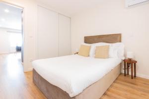 a white bedroom with a large white bed with pillows at Apartamento Porta14 1 in Chaves