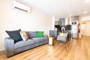 a living room with a gray couch and a kitchen at Apartamento Porta14 1 in Chaves