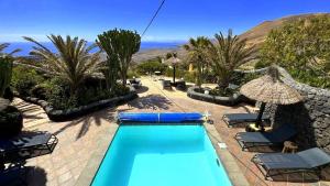 a pool with chairs and umbrellas in a resort at CONCHA - Sonnenbett, Sauna, traumhafter Meerblick, beheizter Pool, Billiard, Tischtennis in La Asomada