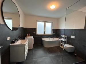 une salle de bain avec une baignoire, un lavabo et un miroir dans l'établissement Ludwig1, à Kindsbach 4 autres photos