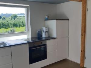 a kitchen with white cabinets and a window at Ferienwohnung Jakob in Kressbronn am Bodensee