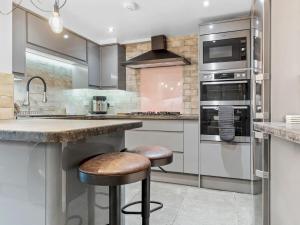 a kitchen with stainless steel appliances and two bar stools at Lovely 2 Bed With Pool Table Ulverston - Pass the Keys in Ulverston