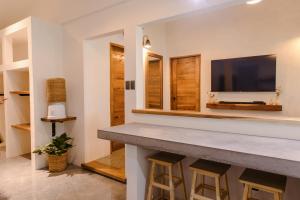 a bar with stools in a living room with a television at Casa Malia Siargao in General Luna