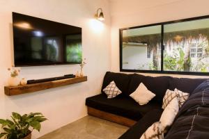 a living room with a black couch and a large mirror at Casa Malia Siargao in General Luna
