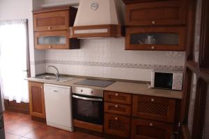 a kitchen with wooden cabinets and a white stove top oven at La Cruz Verde in Tembleque