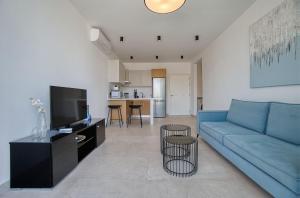 a living room with a blue couch and a kitchen at Avenue 202 1 BED in Paphos