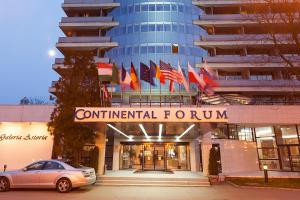 Un coche aparcado delante de un edificio con banderas. en Continental Forum Arad, en Arad