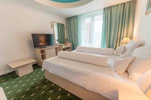 ein Hotelzimmer mit einem großen Bett und einem Fernseher in der Unterkunft Hotel Iadolina in Stana de Vale