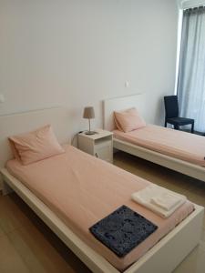 zwei Betten in einem Zimmer mit einem Stuhl und einem Tisch in der Unterkunft Plomari View Stone Apartments in Plomari