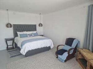 a bedroom with a bed and a chair at Coral Vistas Self Catering Apartments in Gordonʼs Bay +59 photos