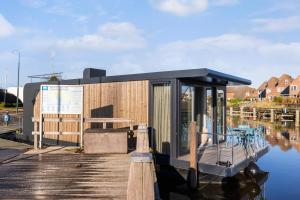 a small house on a dock on the water at Holland Houseboat Lemmer in Lemmer +2 photos