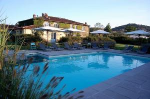 a swimming pool with chairs and umbrellas in front of a house at Residenza Ca De Frati in Arezzo