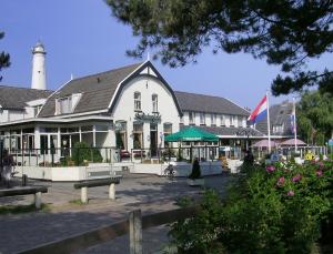 a large white building with a lighthouse in the background at Hotel Cafe Restaurant Duinzicht in Schiermonnikoog