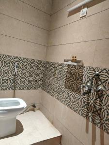 a bathroom with a toilet and a tiled wall at Naari Hotel & Home Stay in Mathura