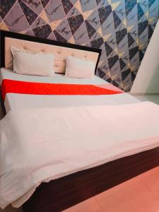 uma cama com lençóis brancos e um cobertor vermelho em The Great Meva Palace Pushkar em Pushkar