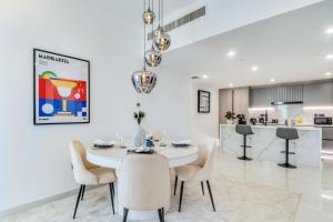 a white dining room with a white table and chairs at Luxurious Brand New 2BR Apartment in Rimal 1 I Steps to the JBR Beach I GYL Holiday Homes in Dubai