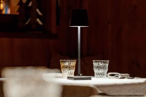 a table with two glasses and a lamp on it at Monaco Sport Hotel in Santo Stefano di Cadore