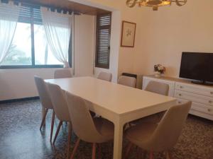 a dining room with a white table and chairs at Primera linea playa in Vinarós