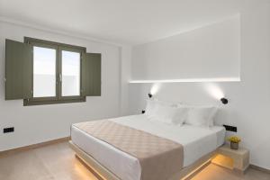 a white bedroom with a bed and a window at Dream of Paros in Parikia +13 photos